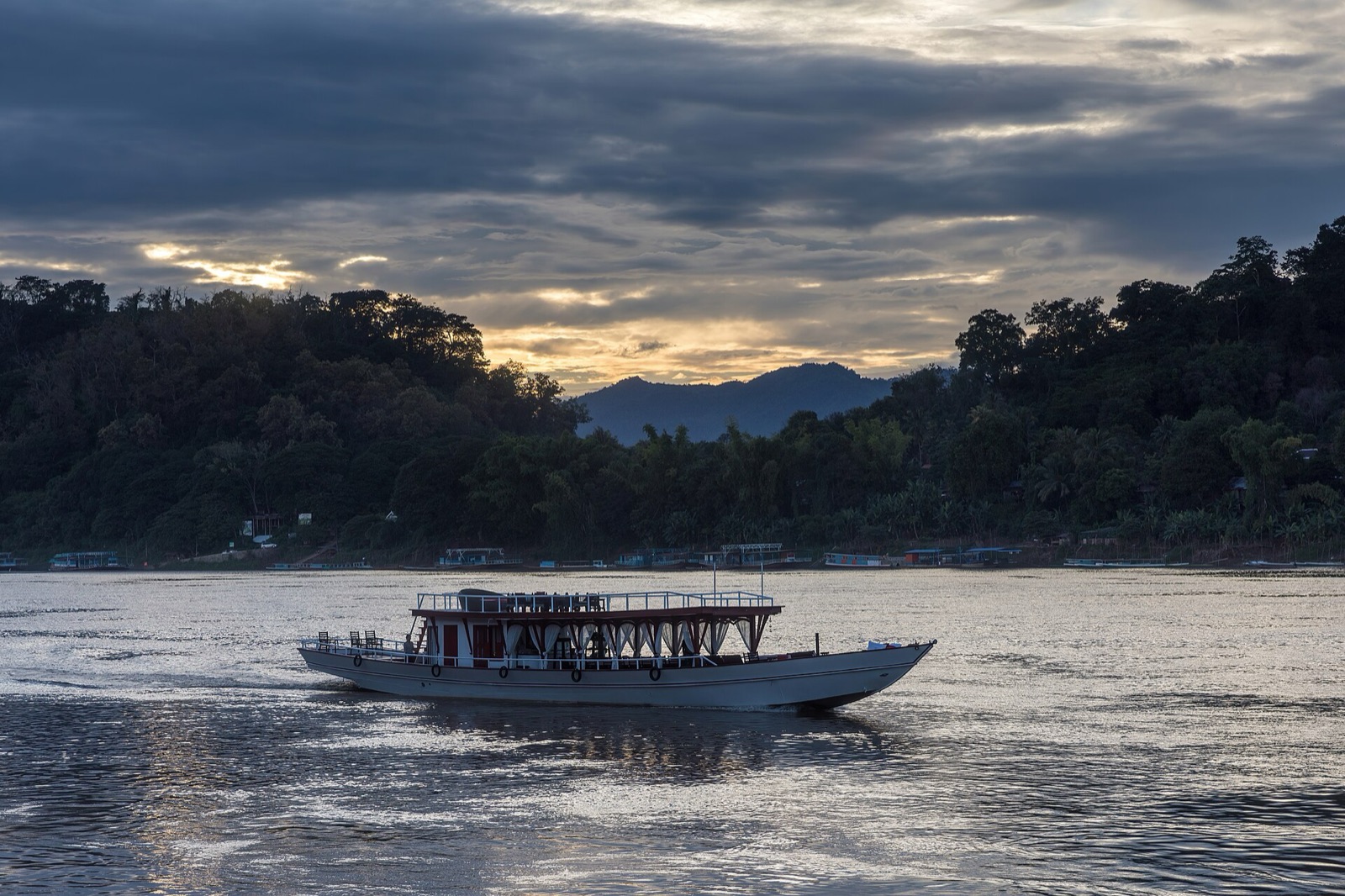A white slow boat on the Mekong near Luang Prabang at sunset