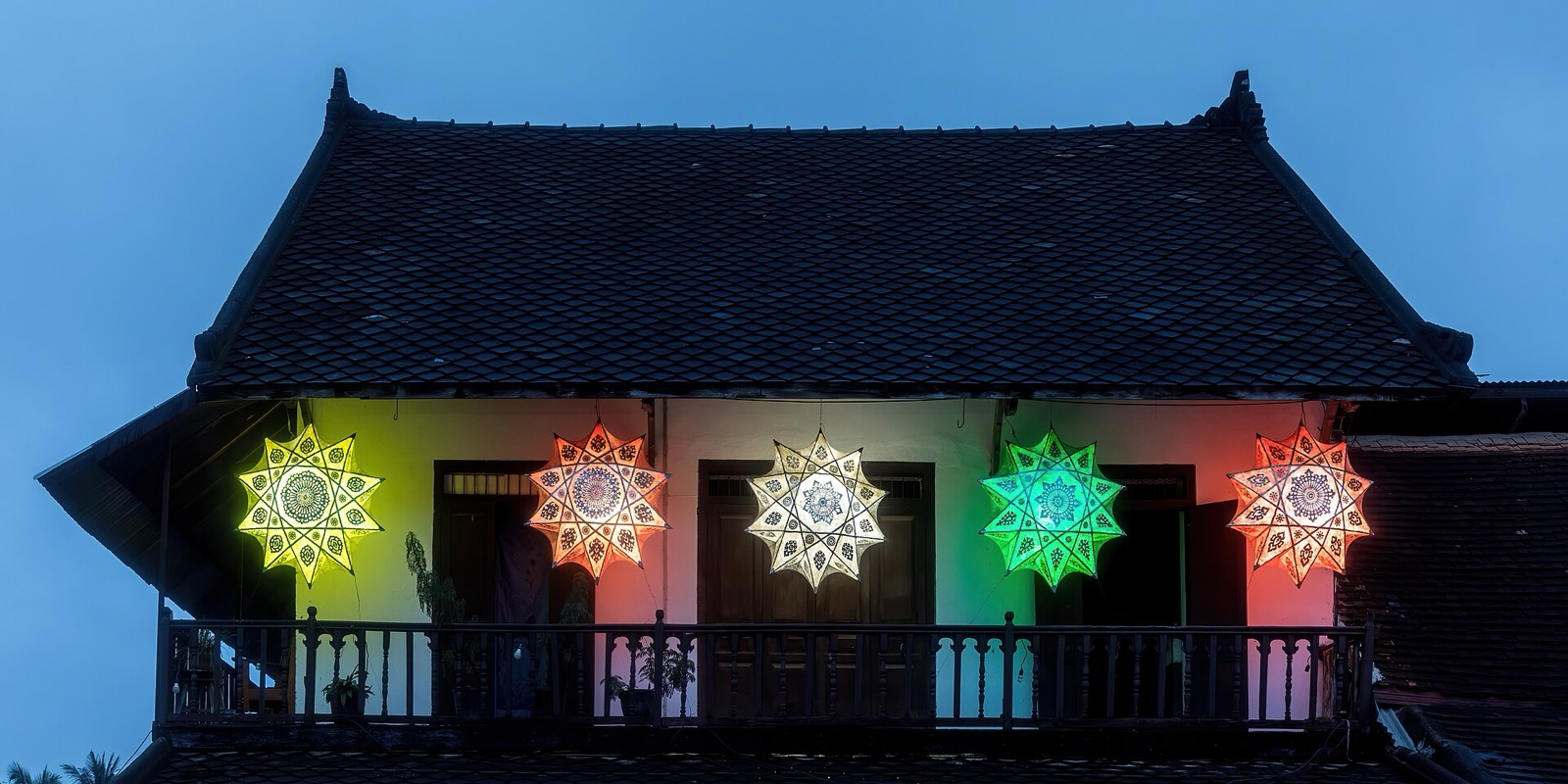 Star-shaped lanterns on a Luang Prabang balcony at blue hour